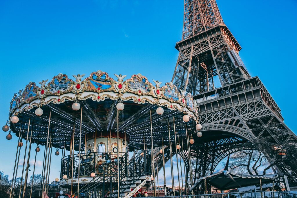 Twilight view of the Eiffel Tower with glowing lights, overlooking the Seine River and Parisian rooftops.