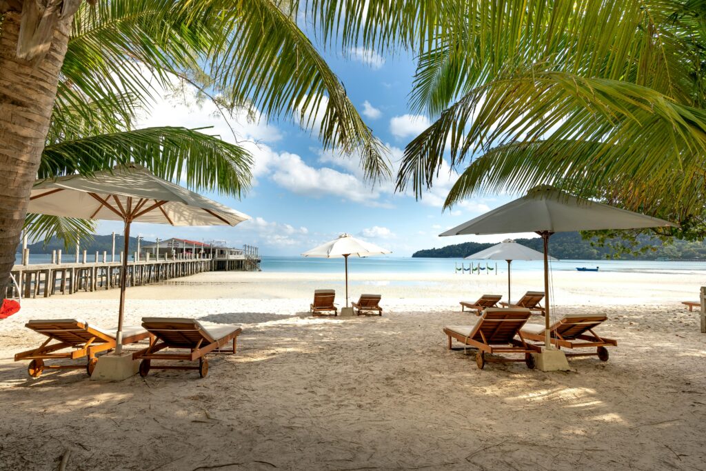 Sun loungers and umbrellas on a serene Phuket beach with clear blue skies and calm turquoise waters.